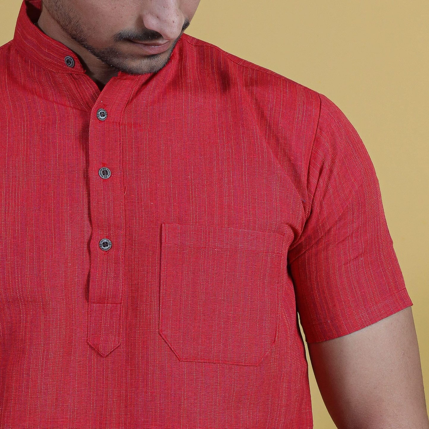 Close-up of red khadi kurta fabric showing fine thread line detailing and front buttons